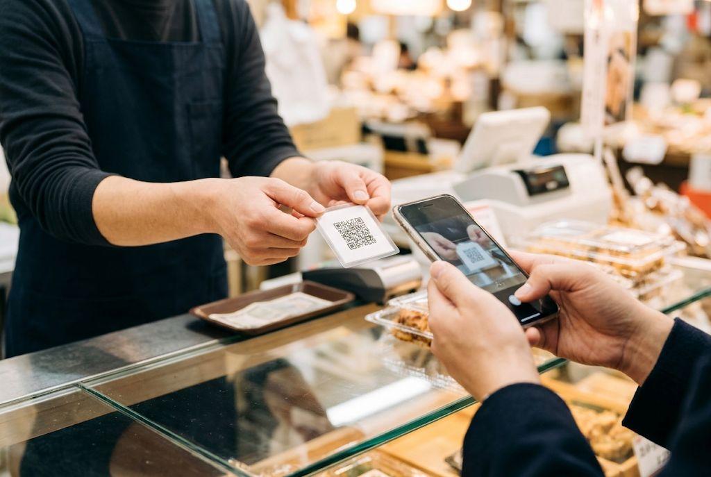 会計時にQRコードのカードを見せ、お客さまがスマートフォンで読み取る場面